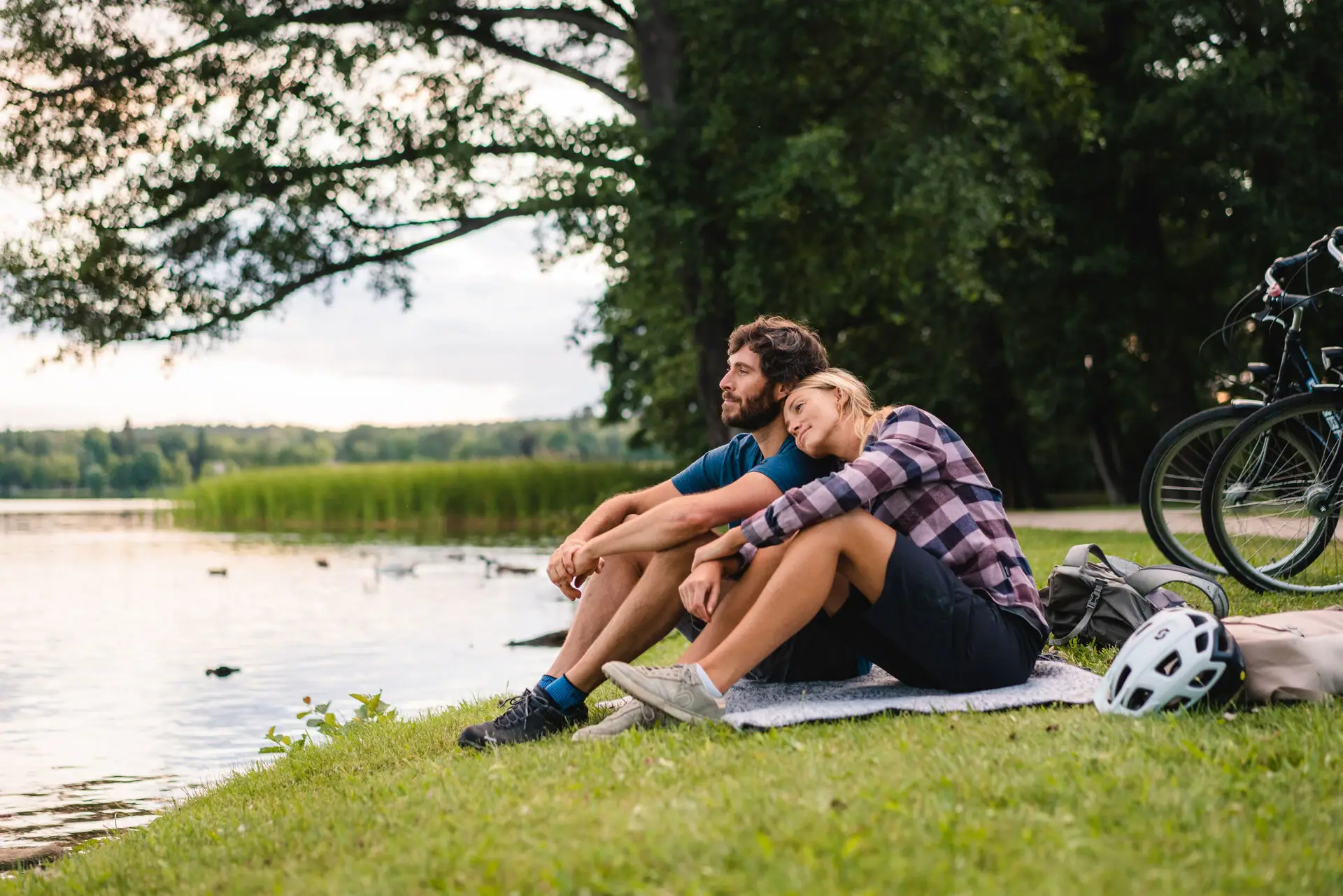 Lakeshore A man and a woman are sitting on a blanket by the lake.