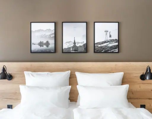 Bed with pillow A bed with white cushions and a wooden headboard, with a picture of a mountain and a ski lift above it.