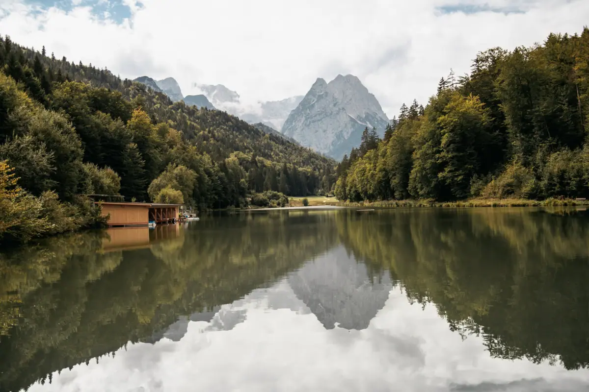 A lake with a cottage and mountains in the background.