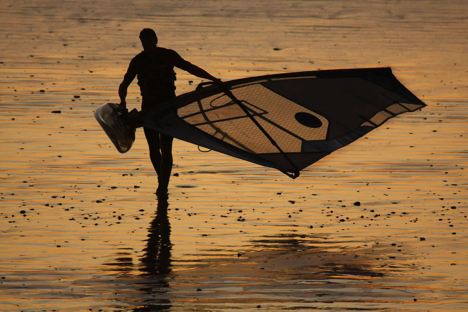 A man holds a sail on the beach.
