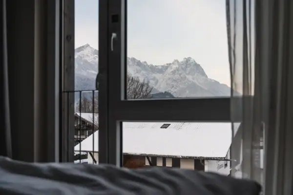 Blick aus einem Fenster auf schneebedeckte Berge