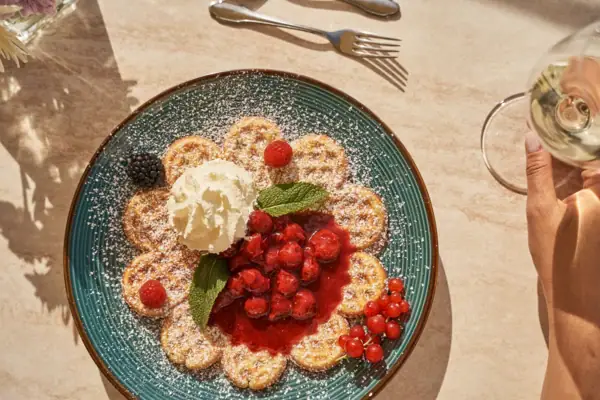 A plate with a waffle topped with berries and whipped cream.