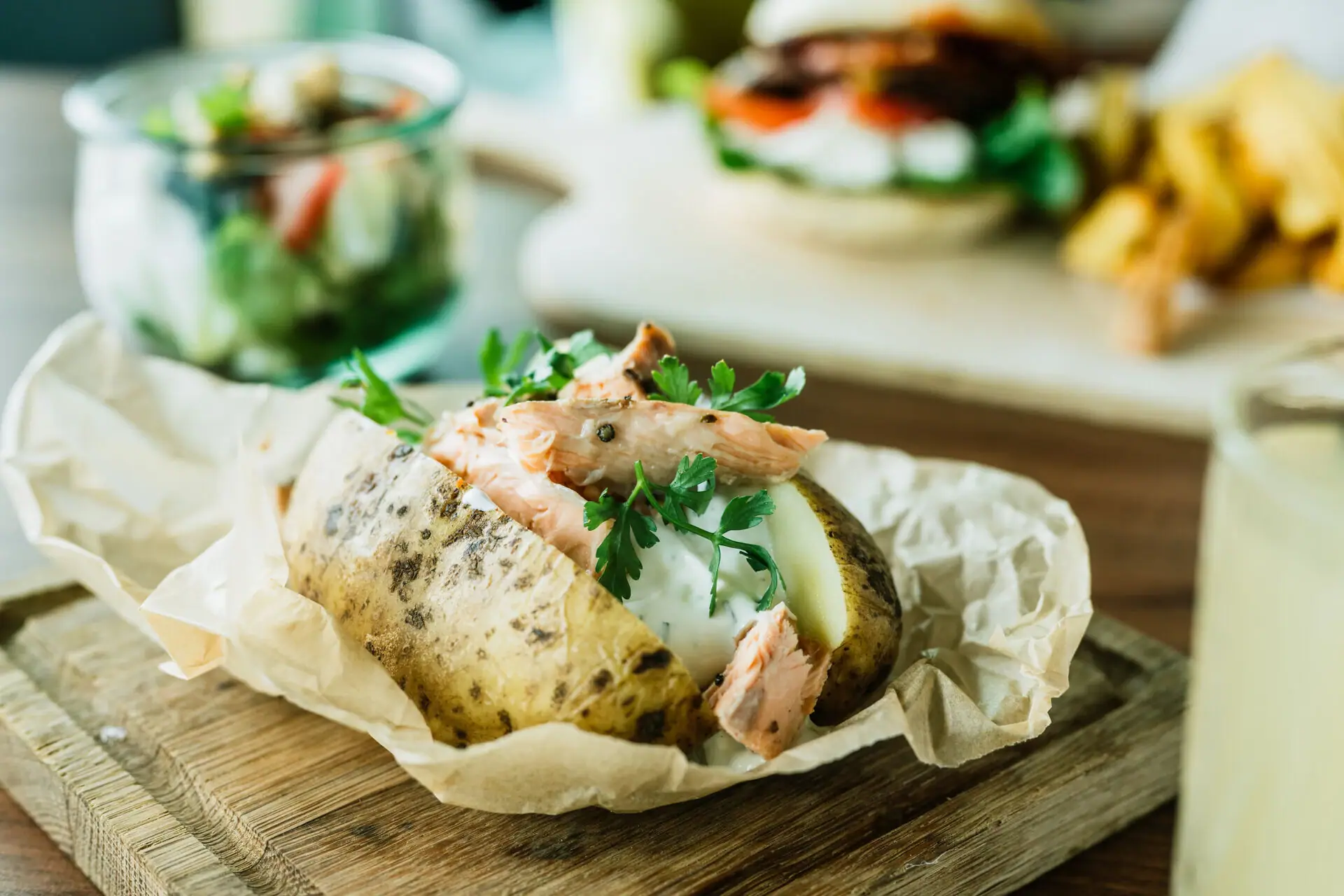 Jacket potato with meat and greens on a wooden board