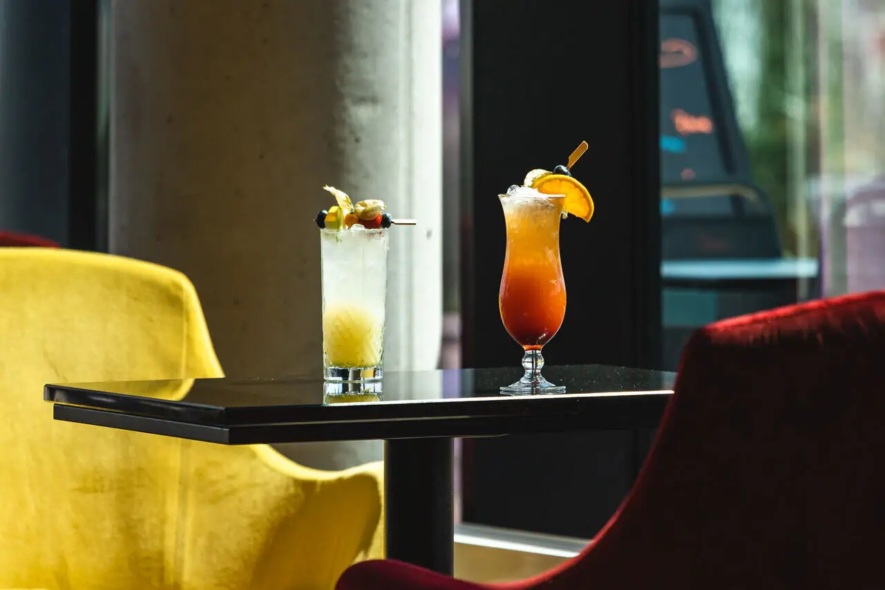 Two glasses with drinks on a table.