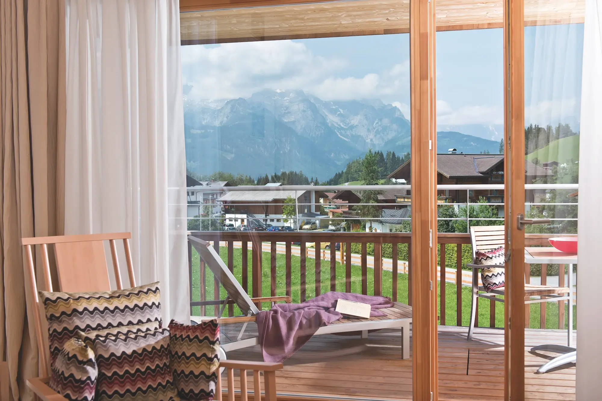 Balcony with view of mountains and trees, equipped with furniture.