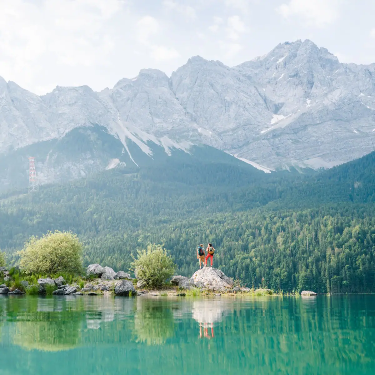 People standing on a rock in front of a lake.