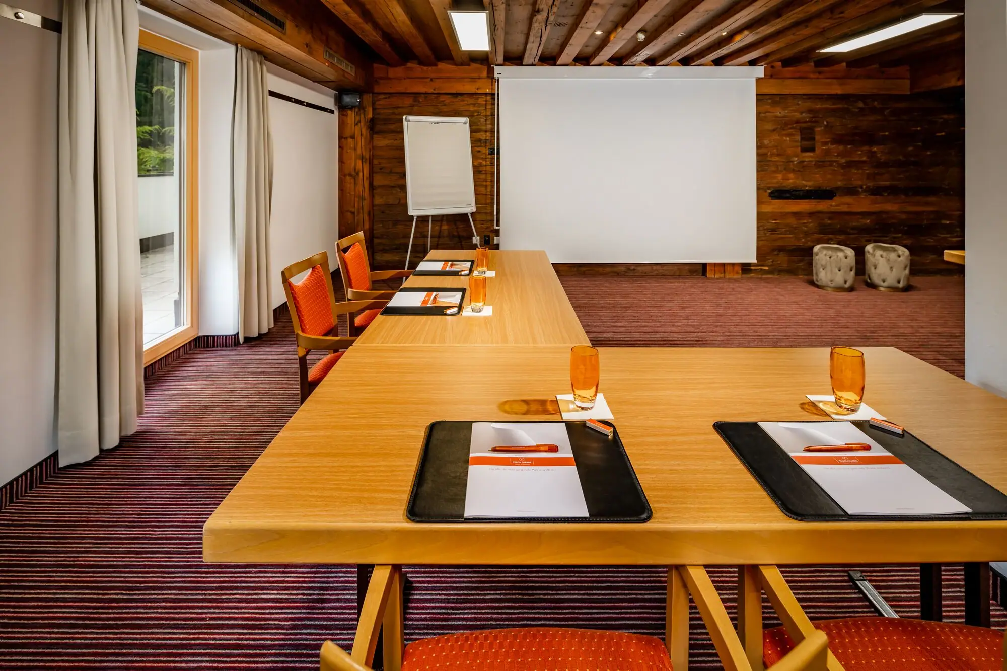A room with a large white screen and several tables.
