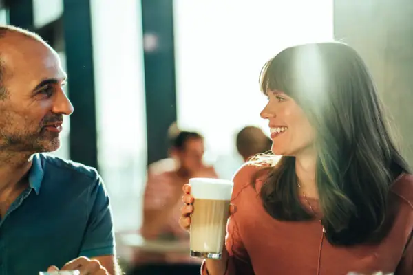 A man and a woman are holding a glass of coffee.