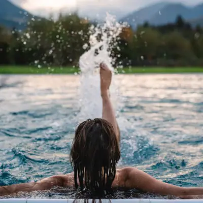 Outdoor pool at aja Ruhpolding A woman swims in a body of water.