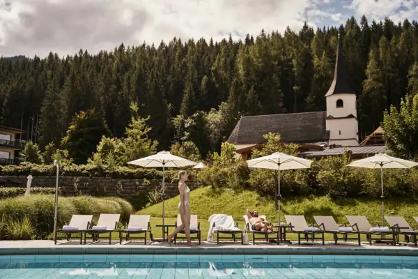 A woman walks along a pool.