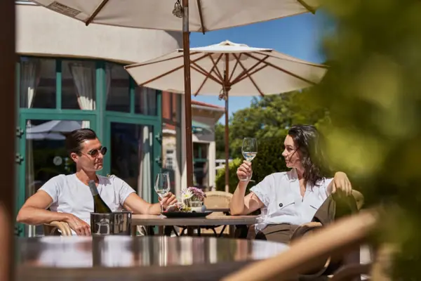 Restaurant A man and a woman are sitting at a table with glasses of wine.