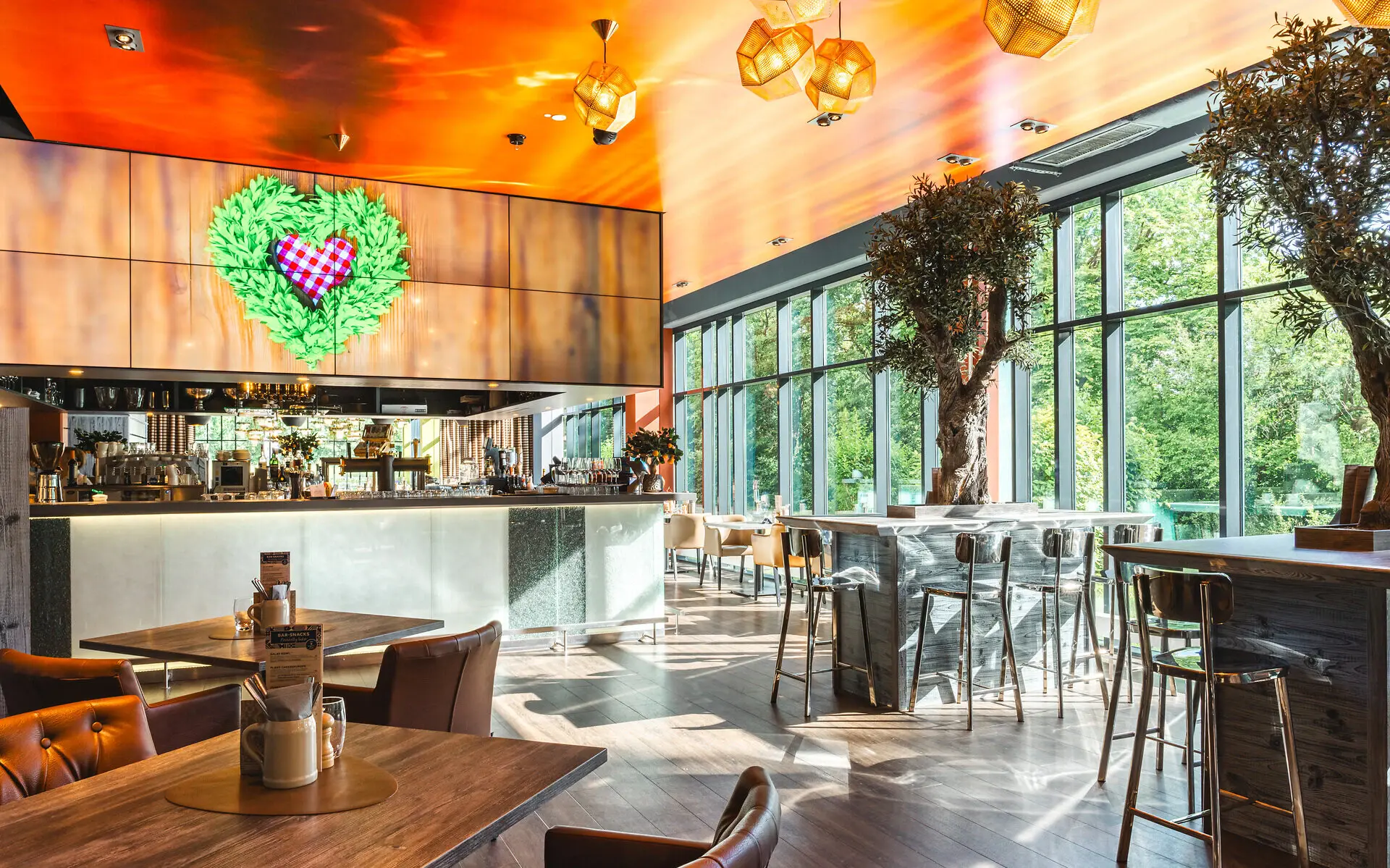 Interior of a room featuring multiple tables and chairs with a prominent tree, designed in a modern style.