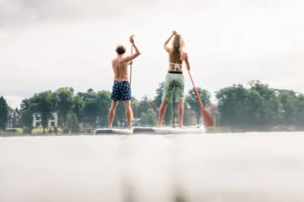 SUP A man and a woman on a paddleboard on the water.