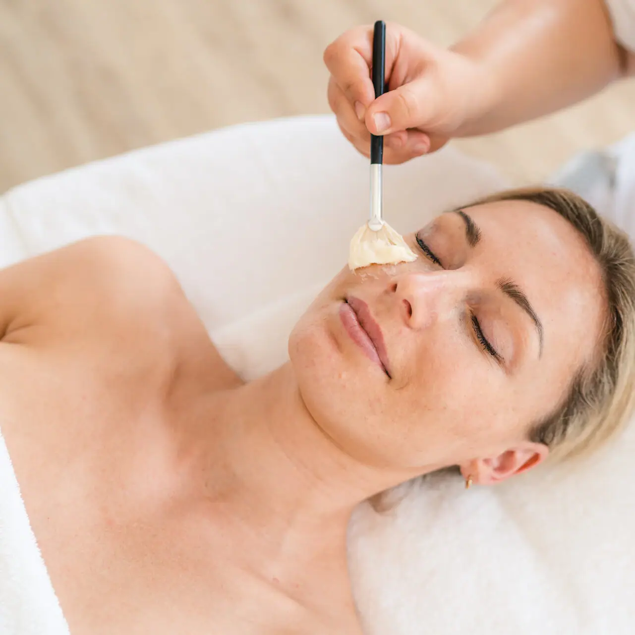 Wellness treatments in Ruhpolding A woman lies with a paintbrush on her face.