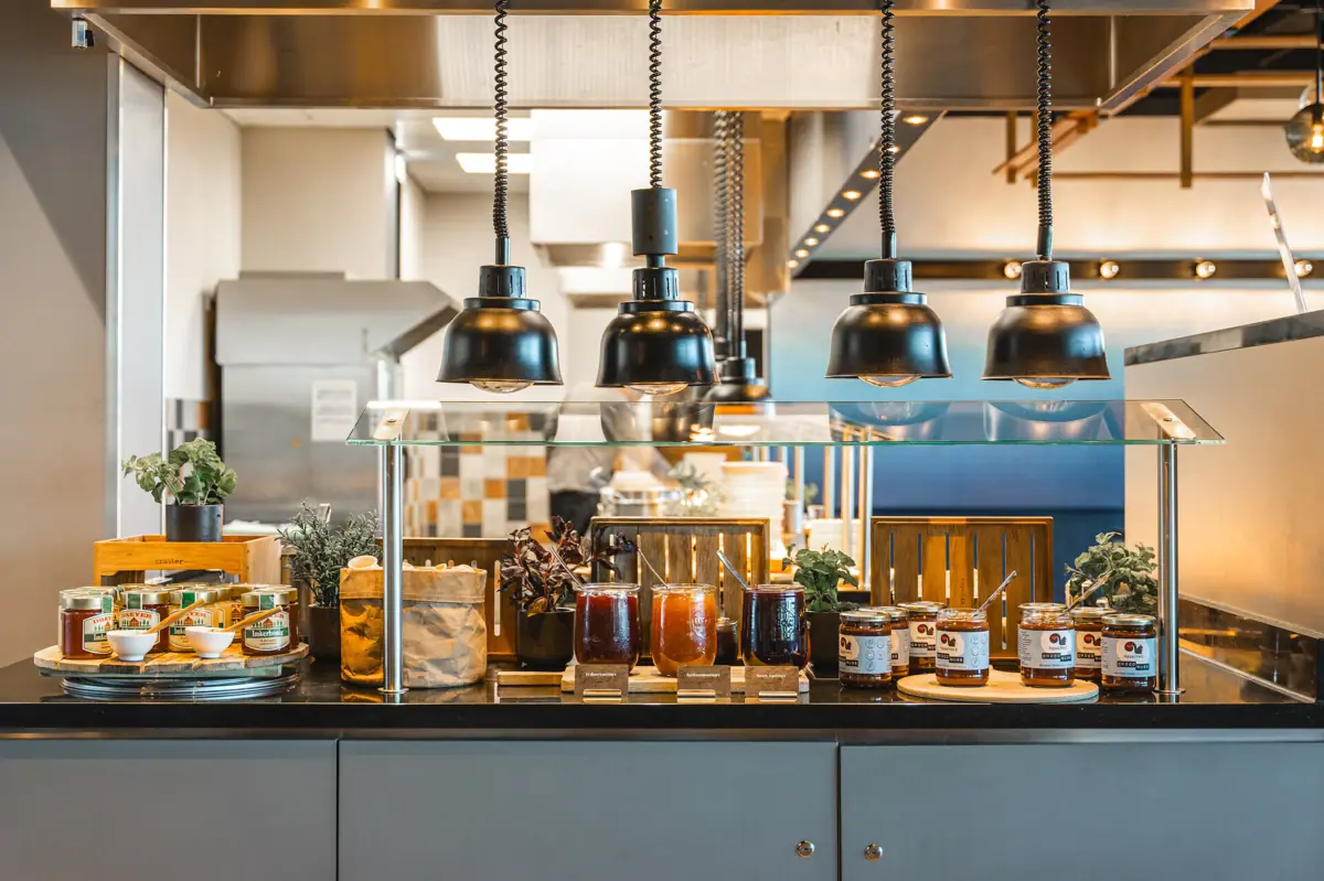 A counter with jam jars and various foodstuffs.