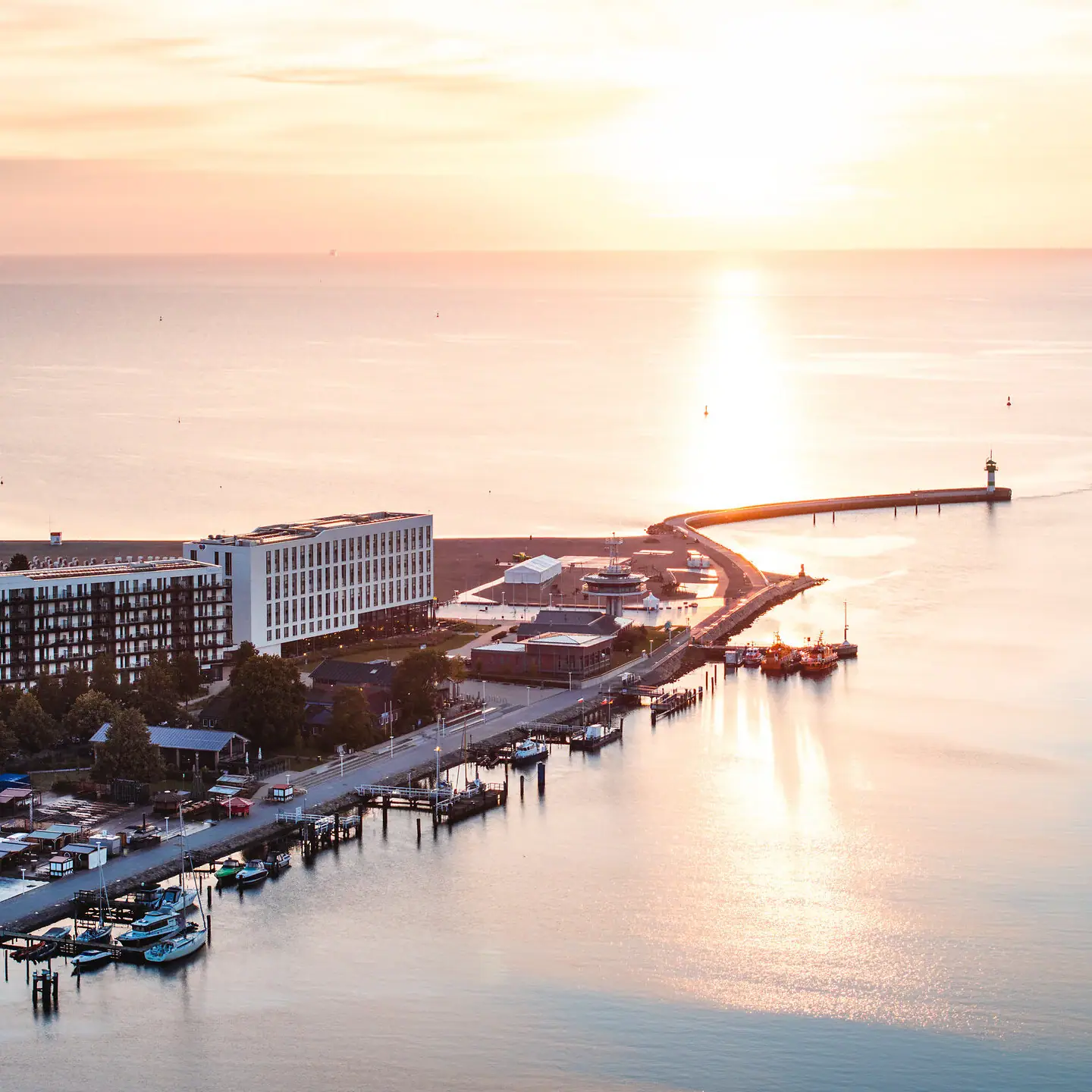 aja Travemünde A body of water with a pier and buildings in the background.