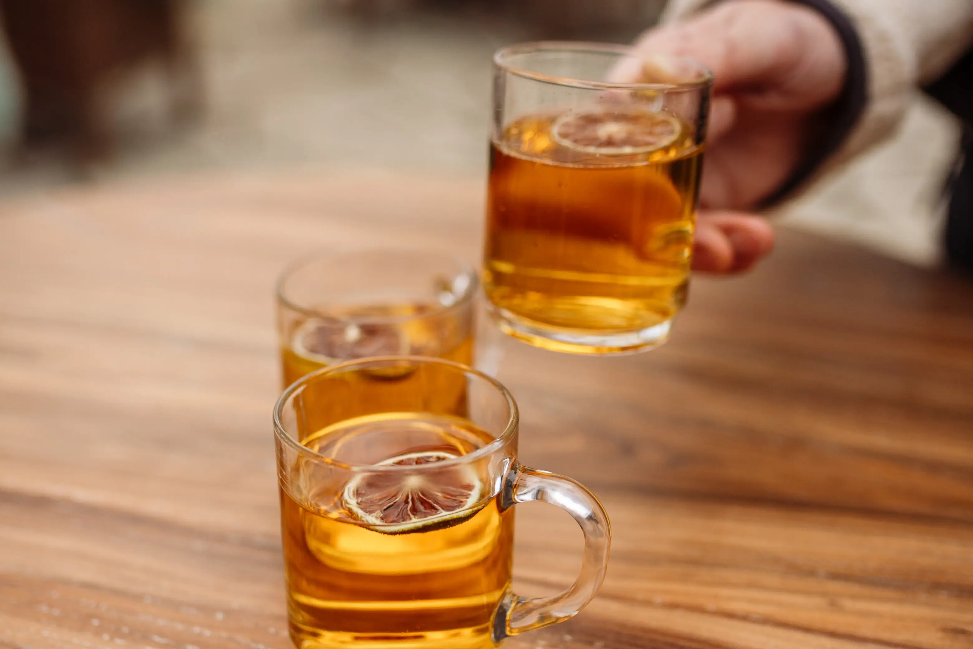 One hand holds a glass with an alcoholic drink.