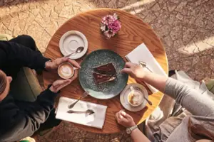 Eine Gruppe von Menschen sitzt an einem Tisch mit Kaffee und Kuchen.