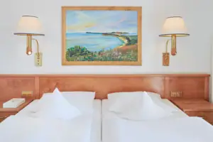 Junior double room landside with balcony A bed with white sheets and a painting on the wall.
