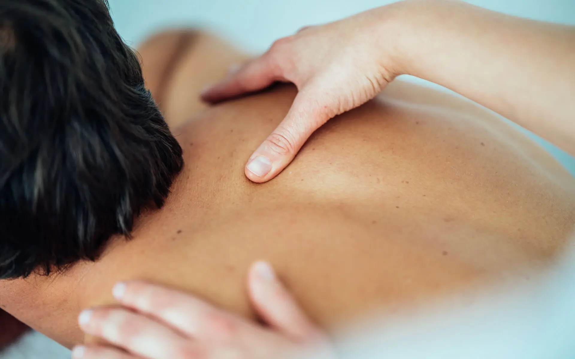 A person receives a back massage in an indoor room.