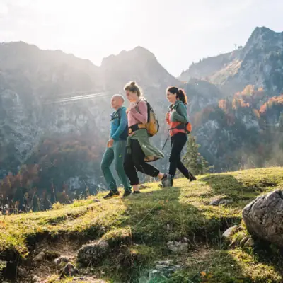 Activities & Experiences A group of people walking on a hill with mountains in the background.