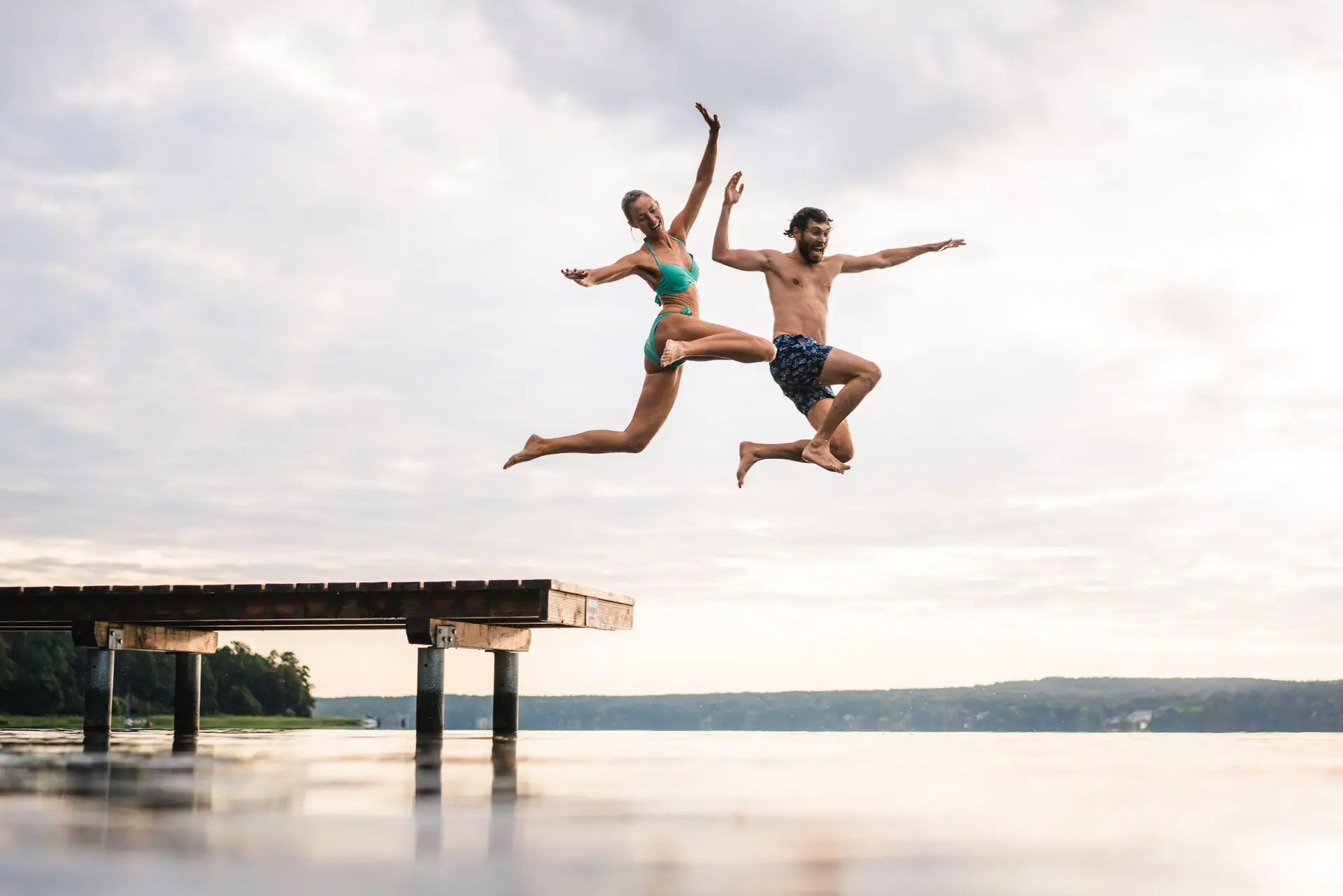 Jump into the lake A man and a woman jump into a footbridge.