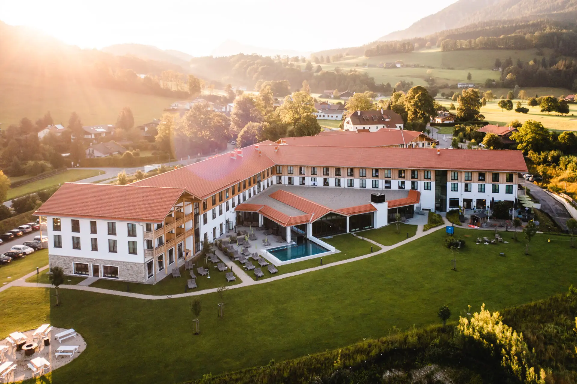 Large building with swimming pool and lawn against a mountain backdrop