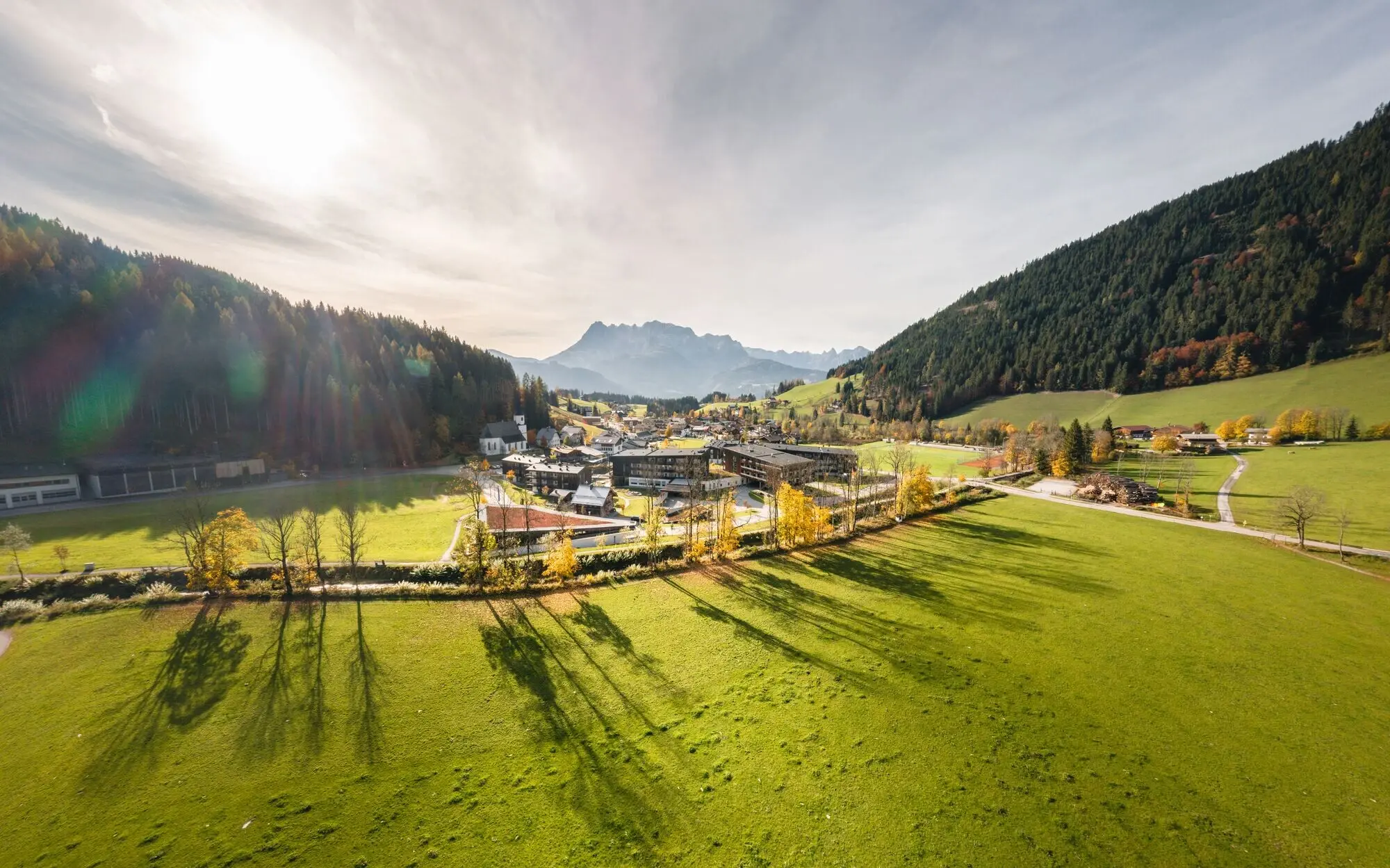 Green valley between mountains with trees and scattered buildings in the background.