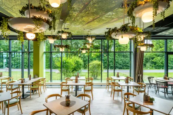 Restaurant Ein Raum mit Tischen und Stühlen, Pflanzen hängen von der Decke.