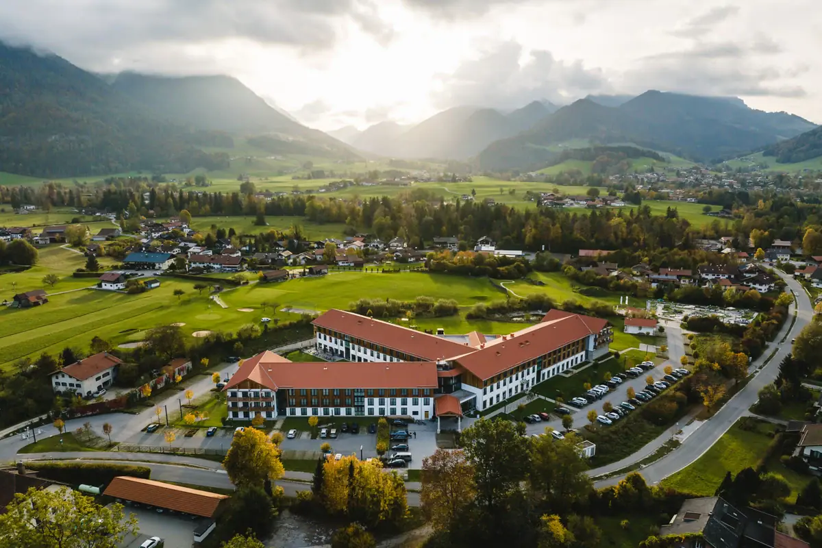 A building with a car park in a valley, mountains in the background.
