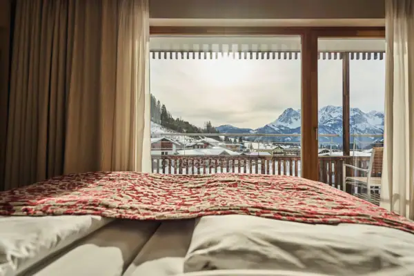 Ein Bett mit Decke und Blick auf schneebedeckte Berge.