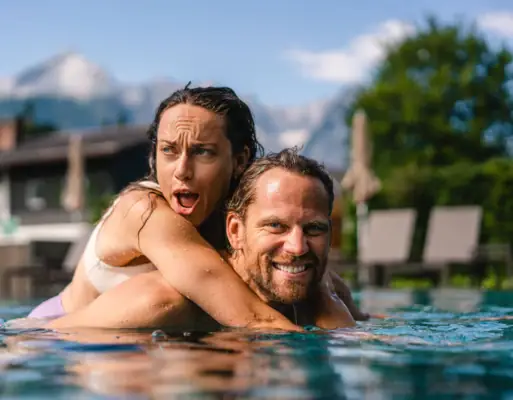 A man and a woman in a pool, both smiling.
