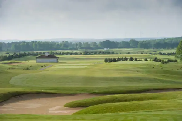 A golf course with a building and trees in the background.
