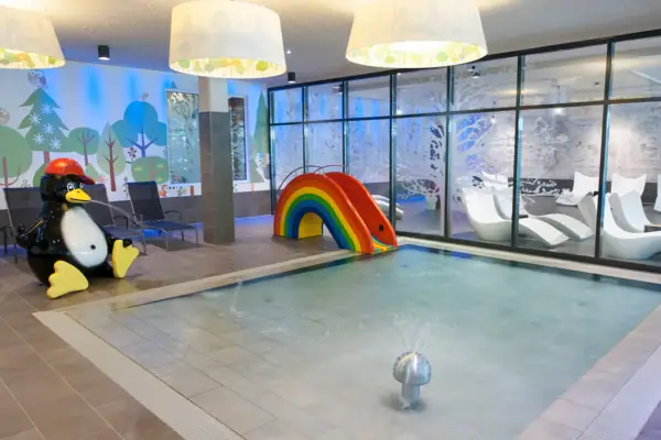 A pool with a slide and a penguin.