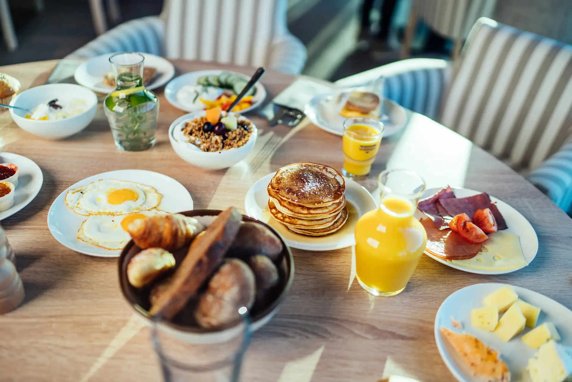 A round wooden table full of food and drinks