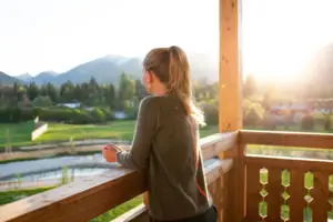 Suite with balcony aja Ruhpolding A woman stands on a veranda and looks down into a valley.