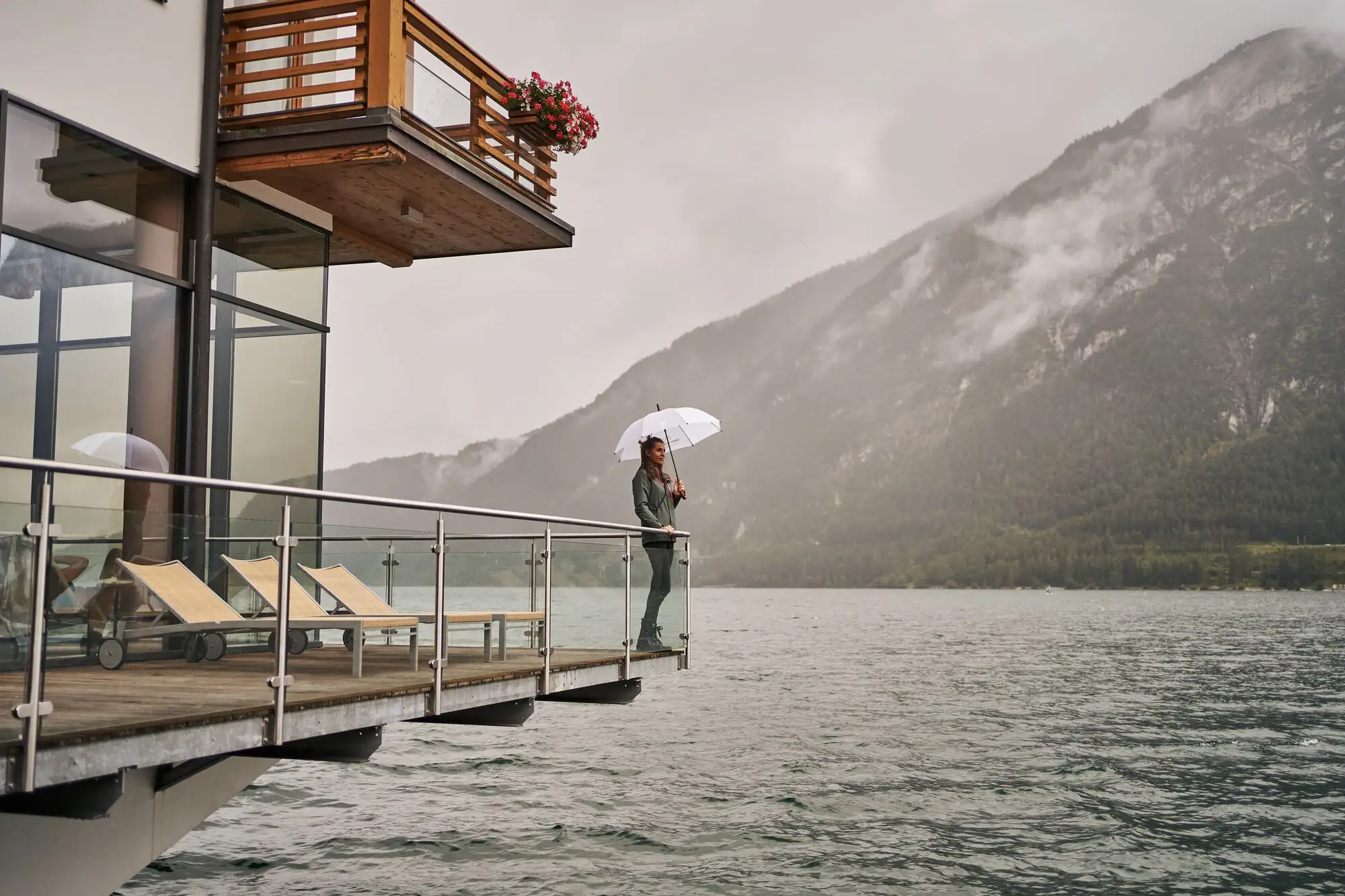 aja Fürstenhaus am Achensee A person stands on a footbridge with an umbrella.