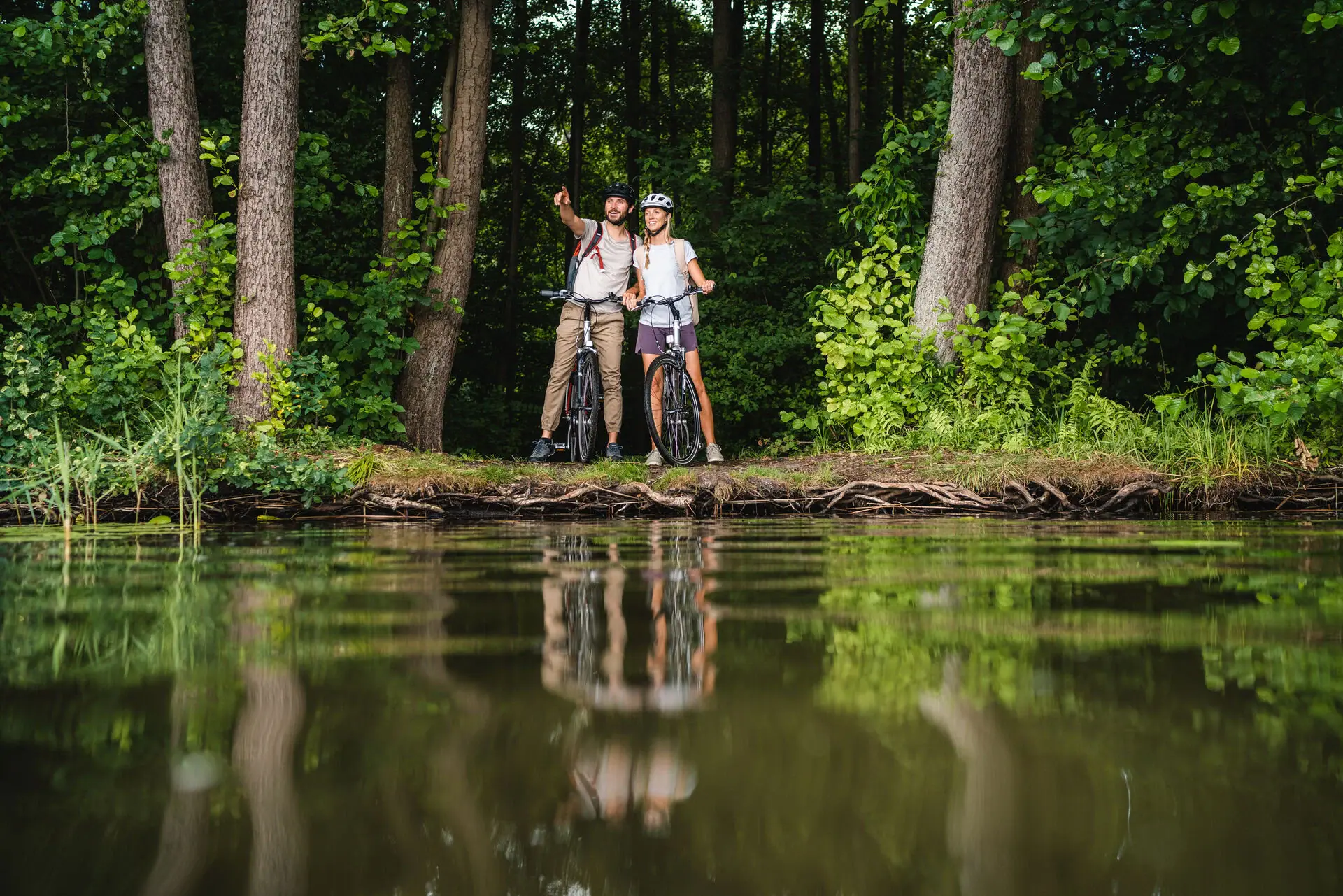 Two people on bicycles by a lake.