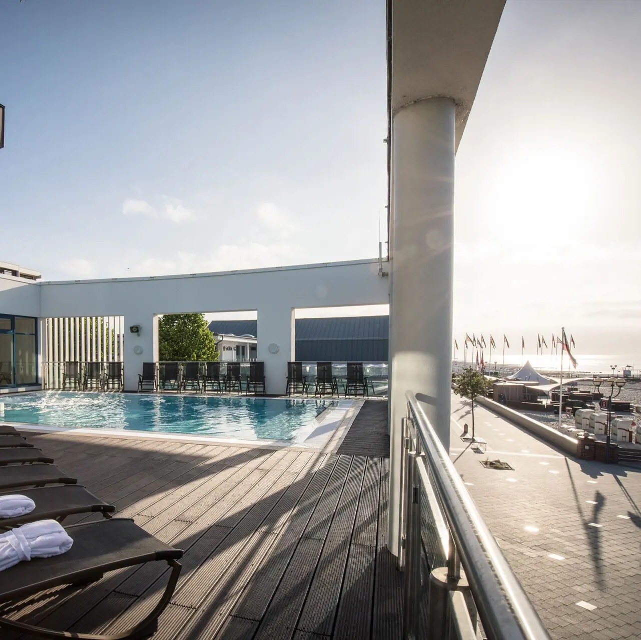 Swimming pool with sun loungers and outdoor wooden terrace.