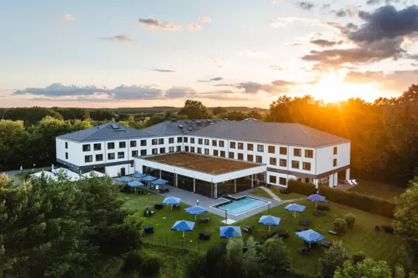 aja Hotel Bad Saarow A building with a swimming pool and parasols.