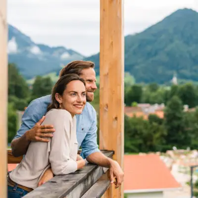 View from the balcony aja Ruhpolding A man and a woman lean against a railing outside.