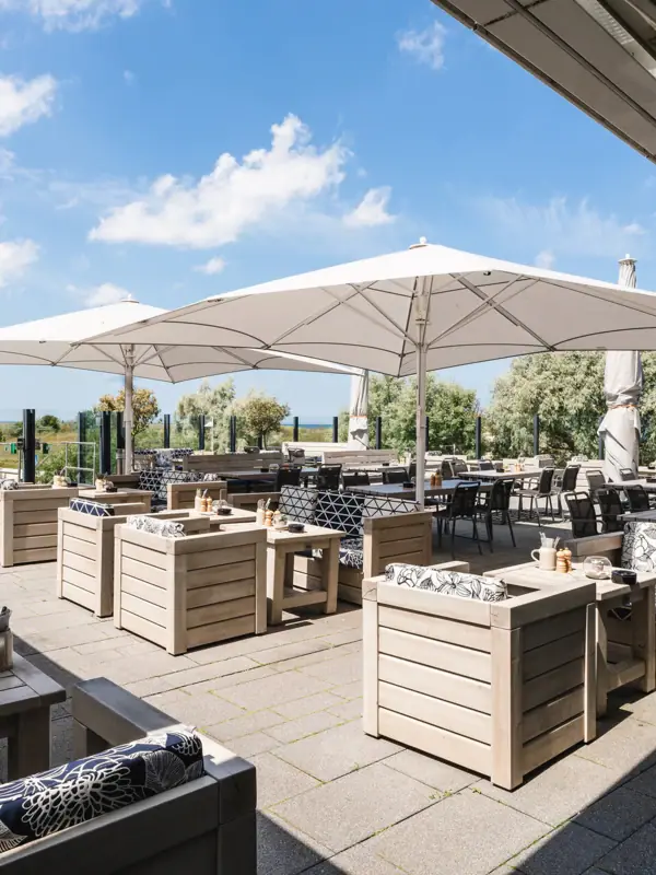 Terrasse im aja Warnemünde Die Terrasse von der The View Bar & Lounge, der aja Strandbar Warnemünde, mit Tischen und Stühlen.
