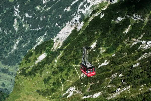 A red cable car gondola in the mountains.