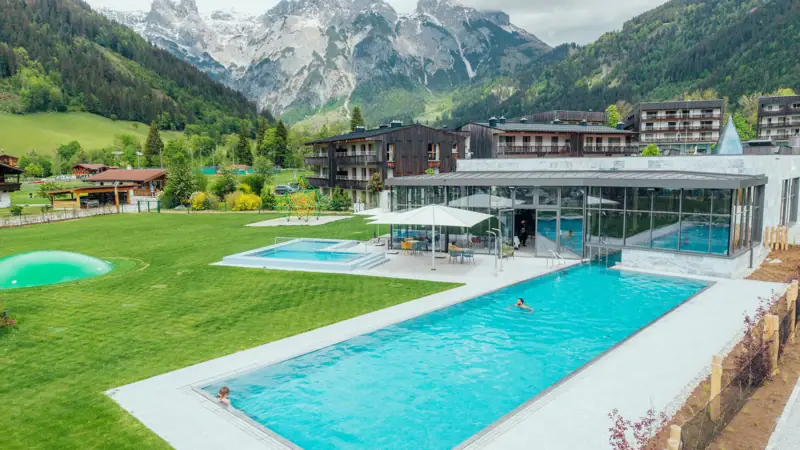 A swimming pool with a building and mountains in the background.