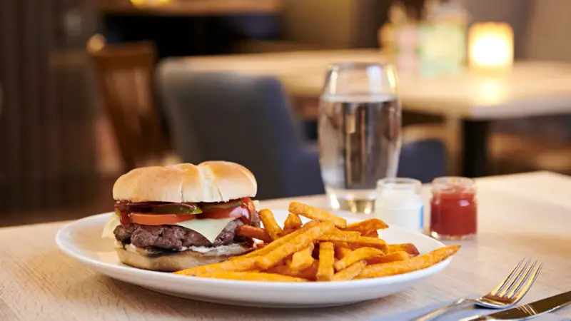 A plate of fast food featuring a sandwich and french fries on a table.