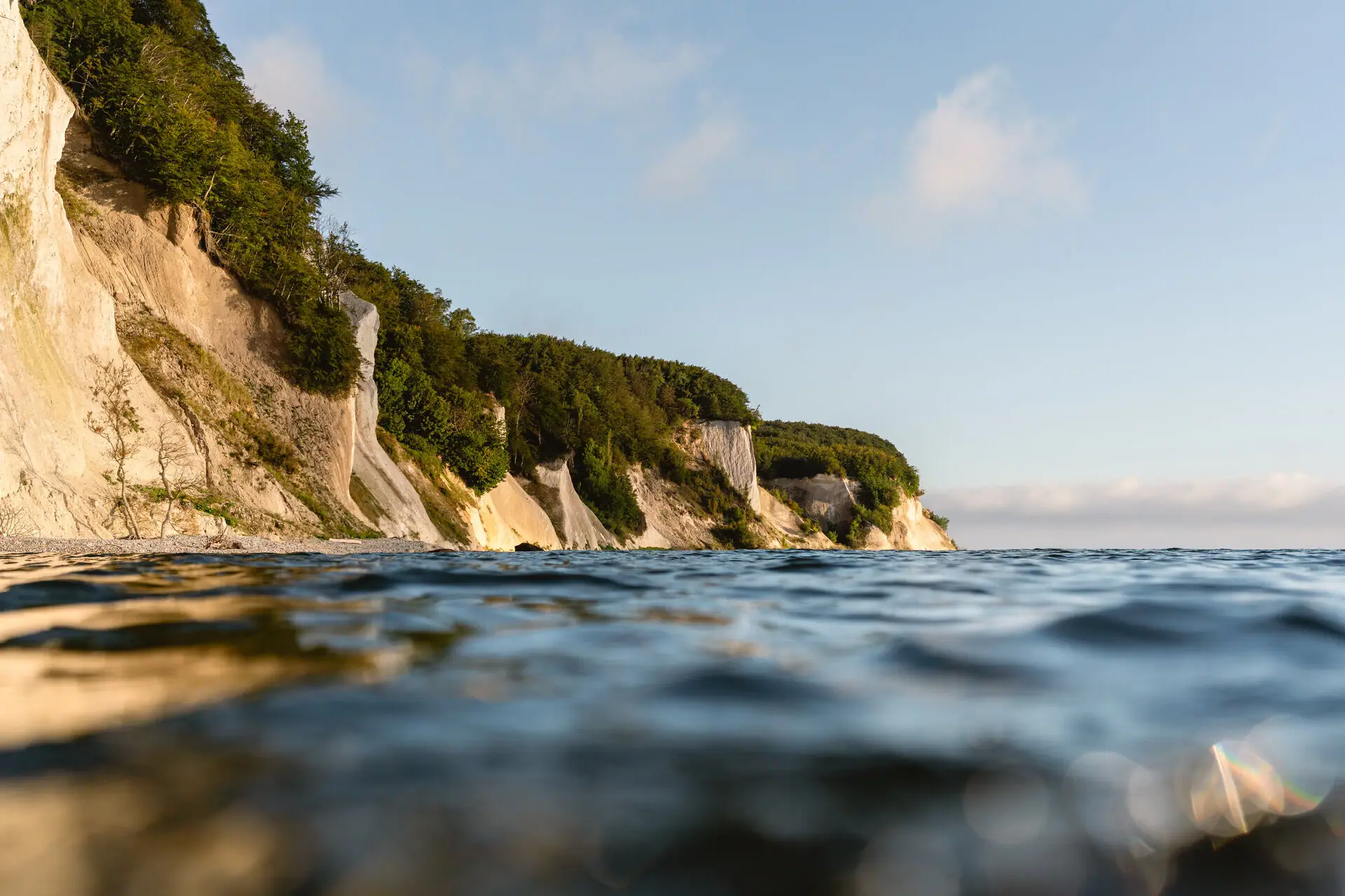 A body of water with a cliff and trees.