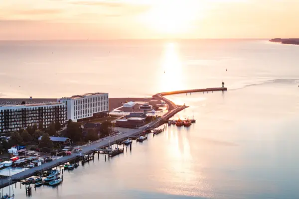 Das aja Travemünde direkt am Wasser gelegen mit einem Leuchtturm im Hintergrund.