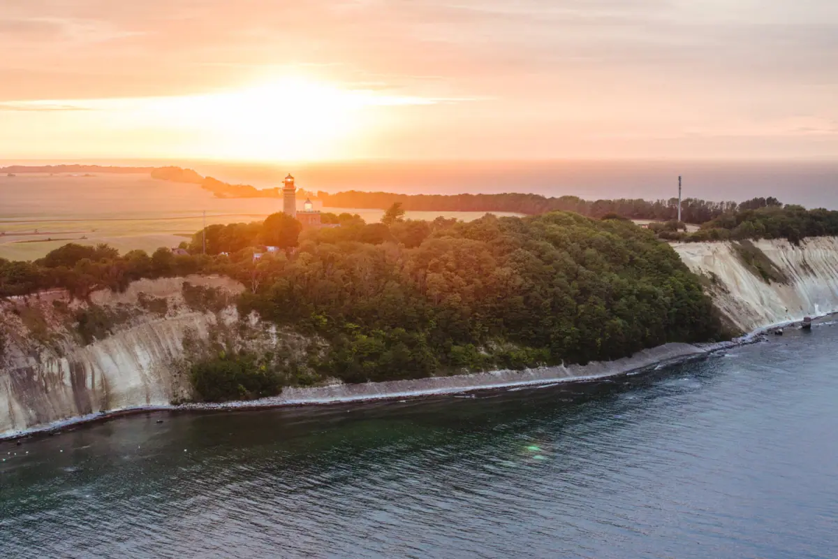 A body of water with a lighthouse on a hill.