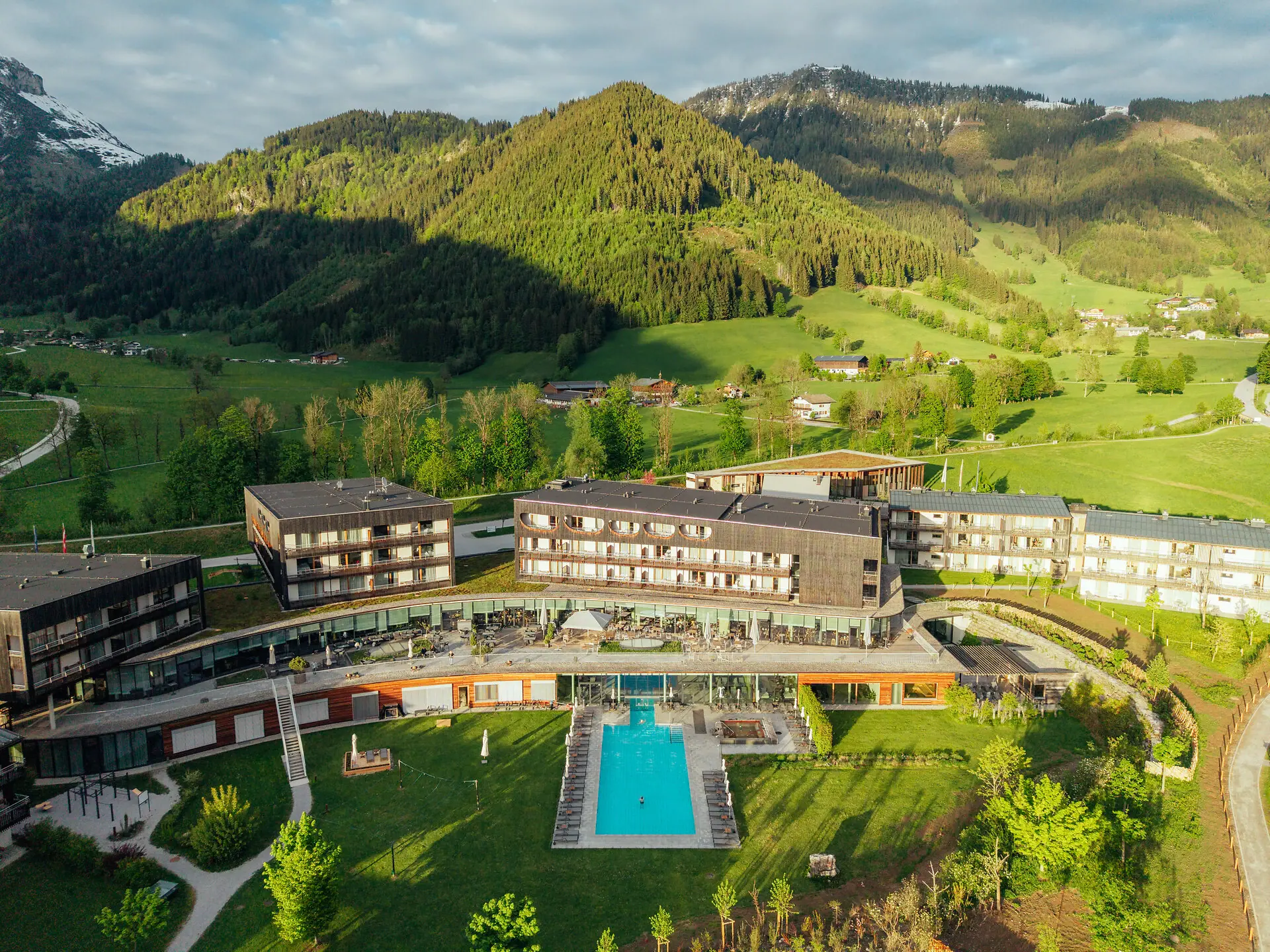 A hotel with a swimming pool set amidst green fields