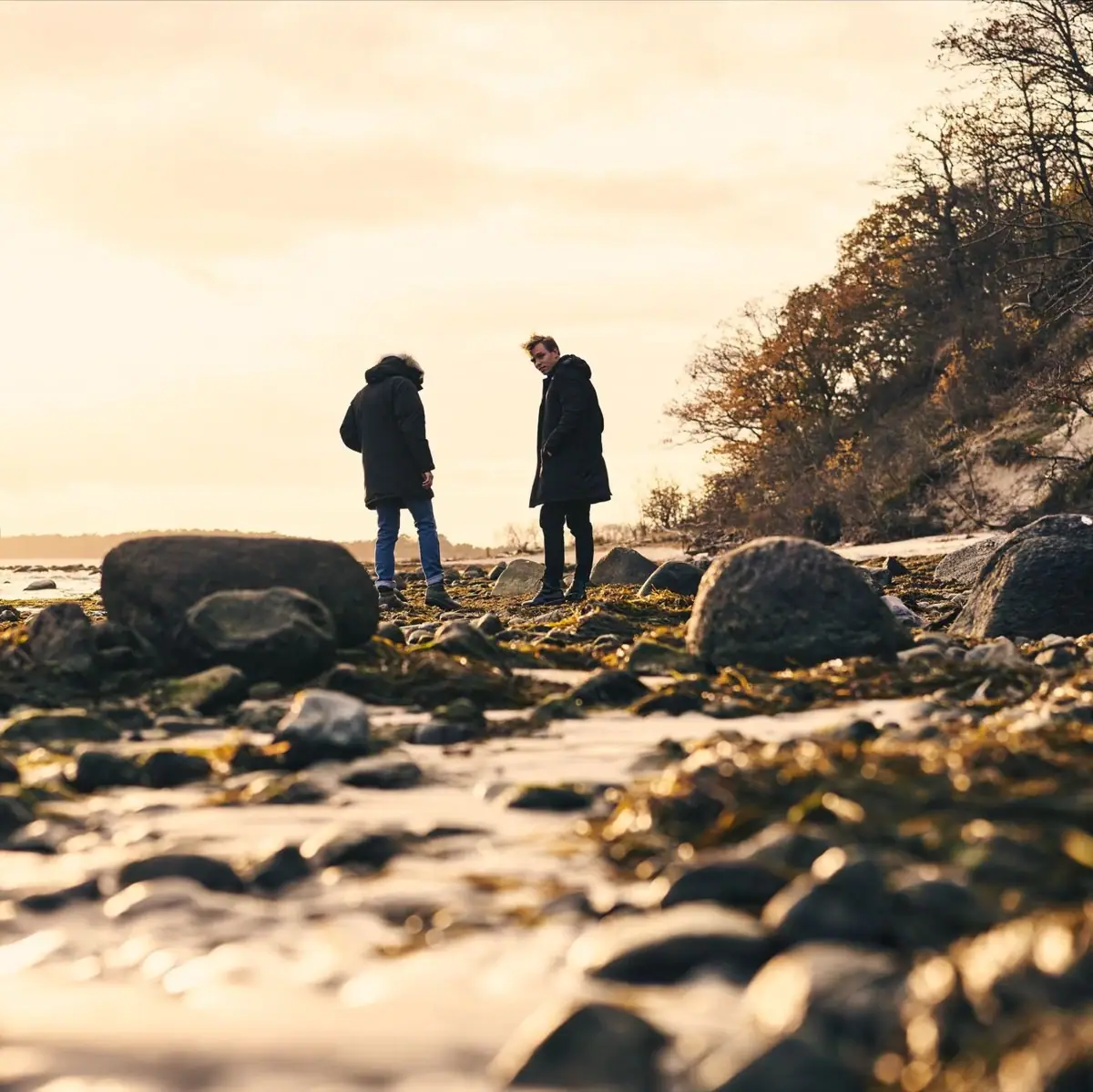 Autumn on the beach A couple stands on a rocky beach.